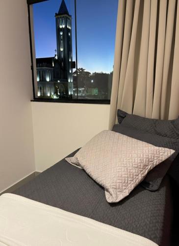 a bedroom with a bed and a window with a clock tower at Oásis urbano in Muriaé