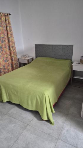 a bed with a green blanket on top of it at Punto de Encuentro in Presidencia Roque Sáenz Peña