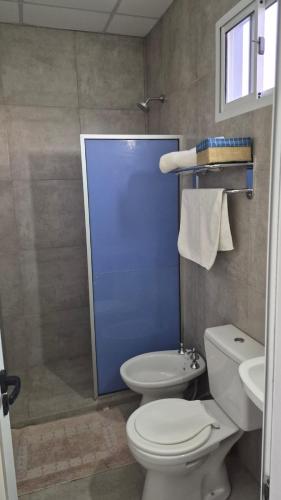 a bathroom with a toilet and a blue door at Punto de Encuentro in Presidencia Roque Sáenz Peña