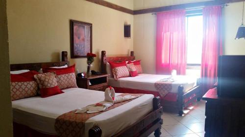 a bedroom with two beds and a window at Matum Hotel & Casino in Santiago de los Caballeros