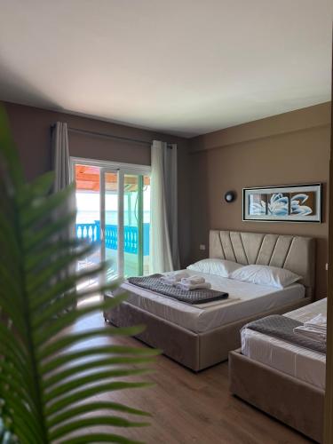 a bedroom with two beds and a balcony at Yamas Hotel "Ex Malibu" in Dhërmi