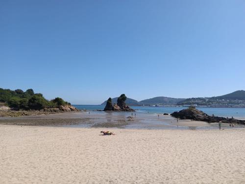 a sandy beach with rocks in the water at Pensión montoxo in Cedeira