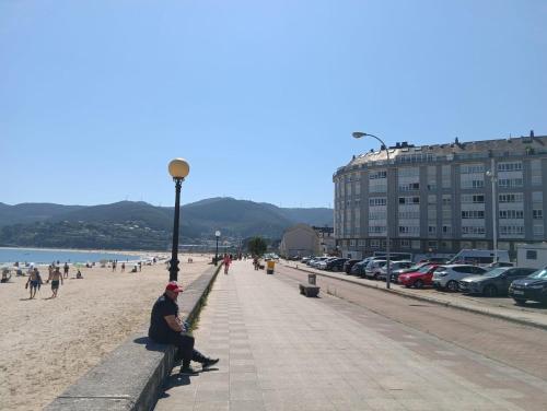 a man sitting on a wall on the beach at Pensión montoxo in Cedeira