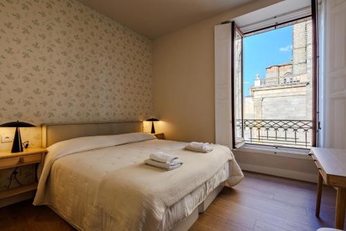 a bedroom with a bed and a large window at apartamentos catedral suite in Ávila