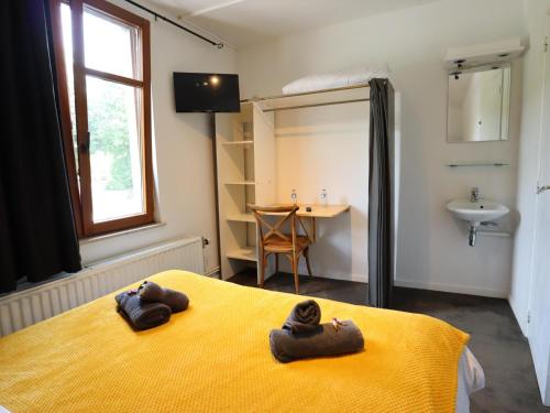 a bedroom with two slippers on a yellow bed at Aux Berges du Lac in Jalhay