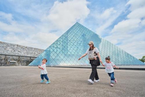 a woman and two children walking in front of a pyramid at 藤乃宿 Villa Moere モエレ沼公園すぐ 愛犬と一緒に泊まれる新築1棟貸し in Sapporo