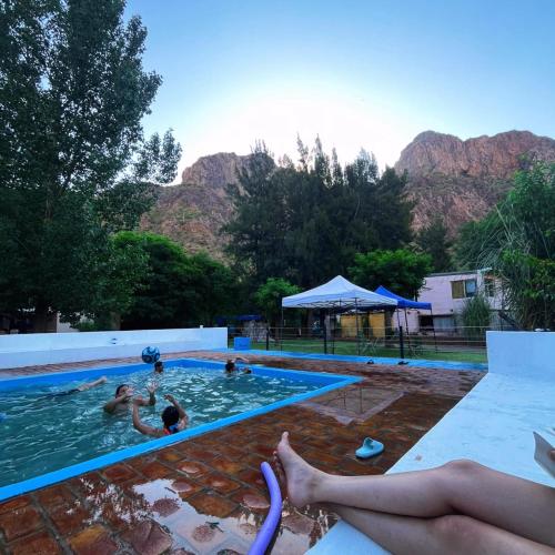 a group of people in a swimming pool with mountains in the background at Cabañas fenix alojamiento in San Rafael