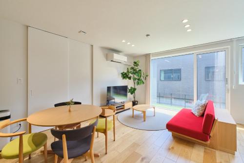 a living room with a table and chairs and a tv at 藤乃宿 Villa Moere モエレ沼公園すぐ 愛犬と一緒に泊まれる新築1棟貸し in Sapporo
