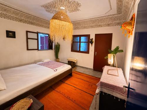 a bedroom with a bed and a chandelier at Farissi's Zawya Surf House in Aourir