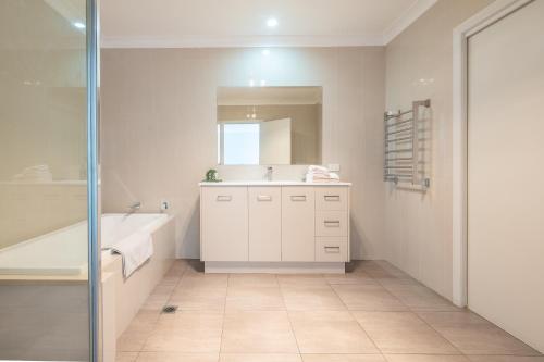 a bathroom with a sink and a tub and a mirror at Kookora Suites in Griffith