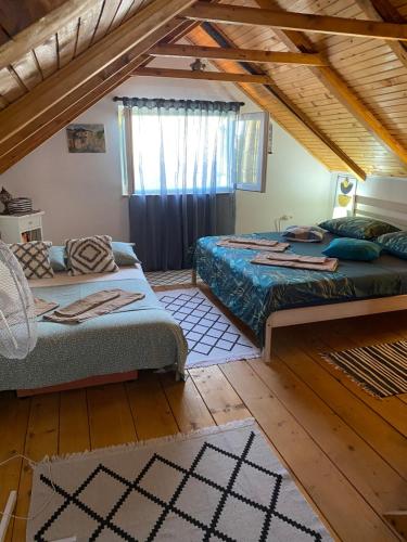 a attic bedroom with two beds and a window at Vila Agroturizam Kućica Mostar in Mostar