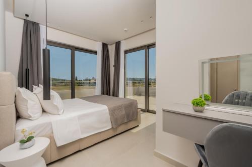 a bedroom with a bed and a desk and windows at Nimar Villas in Gaïtánion