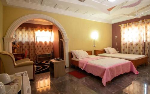 a bedroom with two beds and a chair in it at GLAMOSSAY HOTEL LIMITED SUNYANi in Abesem