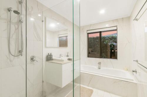 a white bathroom with a shower and a tub and a sink at Salthill in Tweed Heads