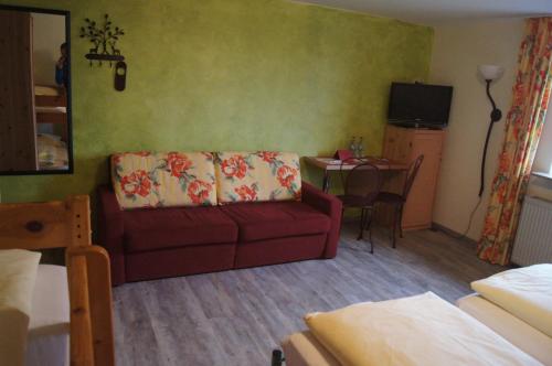 a living room with a red couch and a table at Land-Gast-Hof WALKMÜHLE in Feuchtwangen