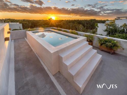 a pool on the roof of a house with the sunset at Villa morada in Tulum