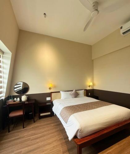 a bedroom with a bed and a desk with a lamp at Gemstay Hotel Hue in Thôn Trường Giang