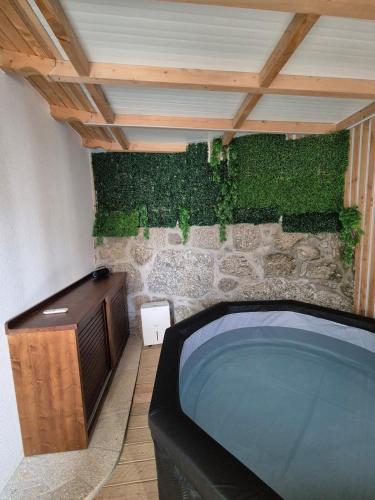 a bathroom with a large tub with a stone wall at Casa da Mexieira em Ponte da Barca in Ponte da Barca