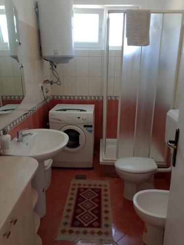 a bathroom with a sink toilet and a washing machine at Casa SOLE in Bihać