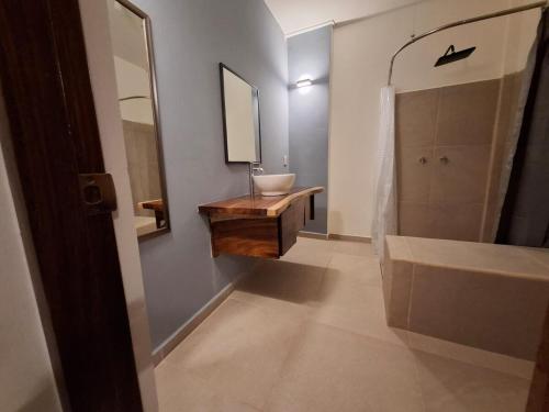 a bathroom with a sink and a tub and a mirror at Huatulco house near beach with pool in Tangolunda