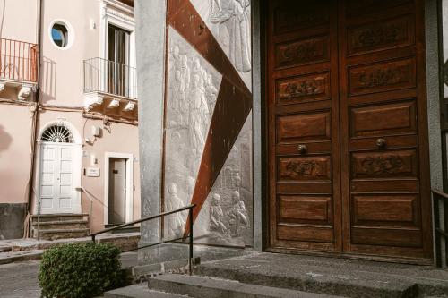 a building with a wooden door and stairs at Corsaro Etna Palace in Motta SantʼAnastasia