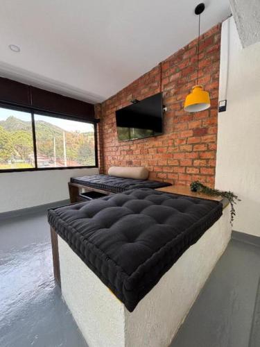 a bedroom with a black bed and a brick wall at Kaza Living Usaquén in Bogotá