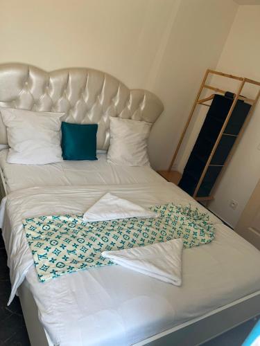a large white bed with blue pillows on it at Résidence les Jardins Secret in Romilly-sur-Seine