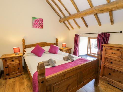 a bedroom with a wooden bed with pink pillows at Beudy Bach in Abergele