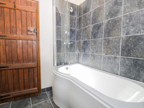 a bathroom with a white bath tub and a wooden door at Beudy Bach in Abergele