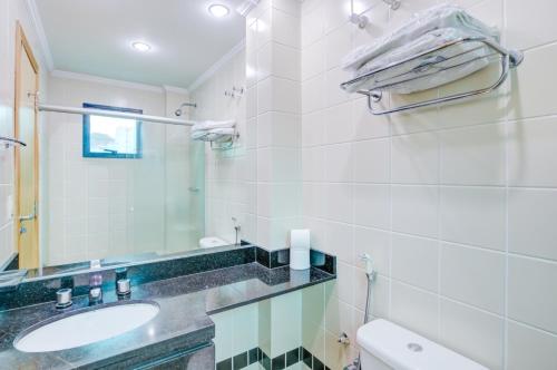 a bathroom with a sink and a mirror and a toilet at Hotel Domani in Guarulhos