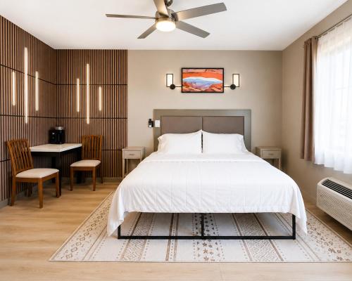 a bedroom with a large bed and a table and a ceiling fan at Bybee's Steppingstone Motel in Tropic