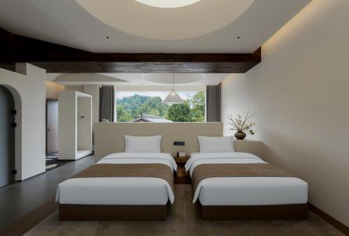 three beds in a room with a large window at Chyanmu Hidden Village Retreat Near The Grand Canyon of Zhangjiajie and Yellow Dragon Cave With Local Culture Village Life Breakfast Quiet Wellness Escape for Urban Travelers Seeking Privacy and Peace in Zhangjiajie