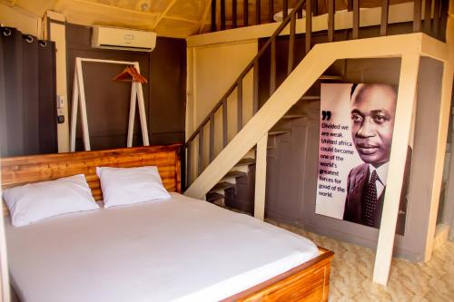 a bedroom with a bed and a staircase with a poster of a man at ASVA BEACH Resort in Grand-Popo