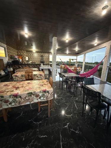 a restaurant with two tables and chairs and a hammock at Caribe de Alter - Hotel & Pousada in Santarém