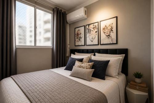 a bedroom with a large bed with four pictures on the wall at Flats Praia Uberlandia - Apt próximo ao Praia Clube - Area de lazer com Portaria 24 horas, piscina, academia, brinquedoteca, churrasqueira e áreas verdes para caminhadas in Uberlândia