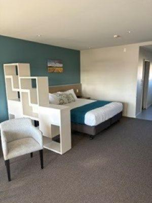 a bedroom with a bed and a chair in it at Northstar Motel in Oamaru