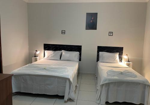 a bedroom with two beds with white sheets at 474 Flats e Suítes Standard in Ipatinga