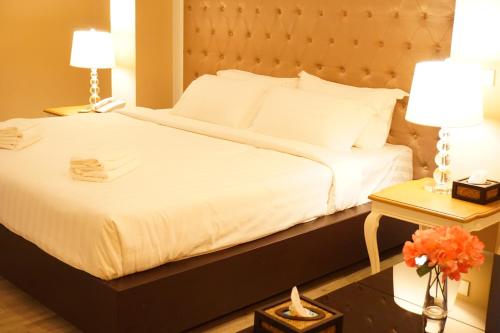 a bedroom with a large white bed and a table at Taris Art Hotel Phrae in Phrae