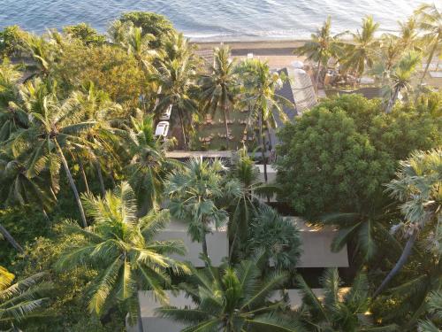 an aerial view of a resort with palm trees and the ocean at Vela Tianyar Boutique Resort - Oceanfront in Tianyar