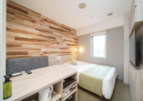 a bedroom with a bed and a wooden wall at Super Hotel Sendai Hirose Dori in Sendai