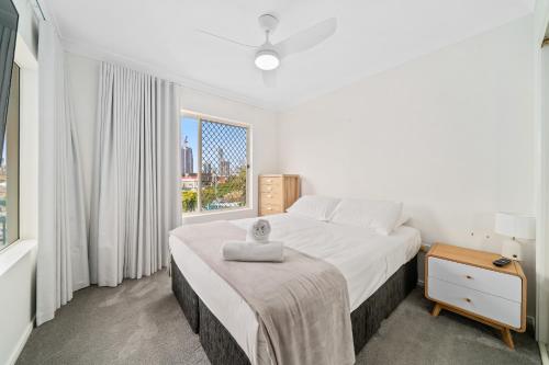 a white bedroom with a large bed and a window at Paradise Isles in Gold Coast