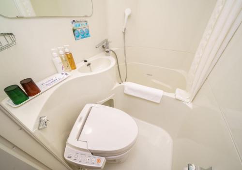 a white bathroom with a toilet and a sink at Super Hotel Sendai Hirose Dori in Sendai