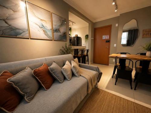 a living room with a gray couch with pillows at Flats Praia Uberlandia - Apt próximo ao Praia Clube - Area de lazer com Portaria 24 horas, piscina, academia, brinquedoteca, churrasqueira e áreas verdes para caminhadas in Uberlândia