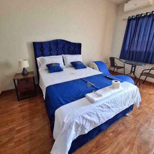 a bedroom with a large blue bed with blue pillows at Hotel Delcor Suite in Piura