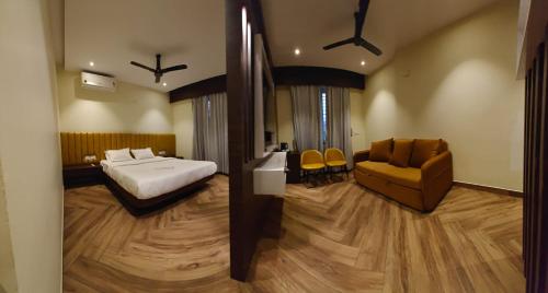 a bedroom with a bed and a couch and a chair at S K Legacy Hotel in Mysore