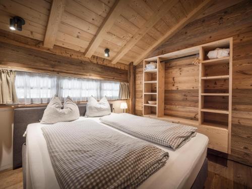 a bedroom with a large bed and wooden walls at Modern chalet in the willow roof in Leutasch
