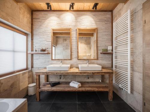 a bathroom with two sinks and two mirrors at Modern chalet in the willow roof in Leutasch