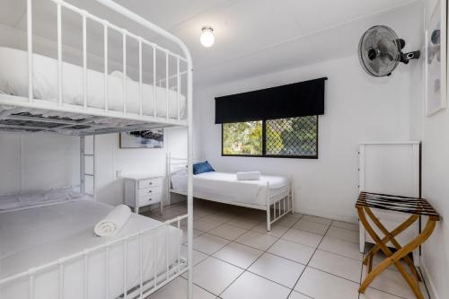 a white bedroom with two bunk beds and a window at A Lure - 100m to Main Beach in Agnes Water