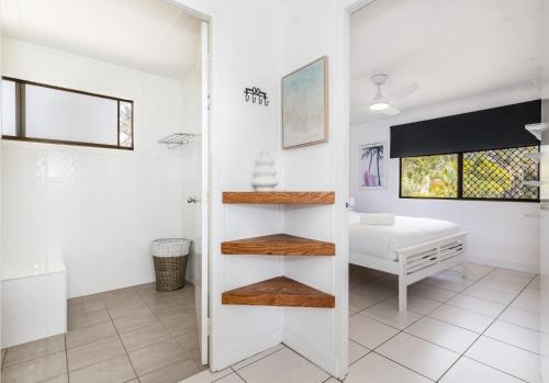 a bathroom with white walls and wooden shelves at A Lure - 100m to Main Beach in Agnes Water