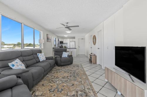 a living room with a couch and a flat screen tv at Seascape U7 in Golden Beach